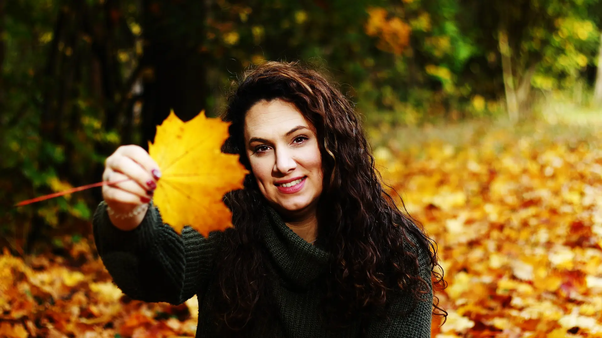 Familiencoach Liza Bruns hält ein herbstliches Blatt vors Gesicht.